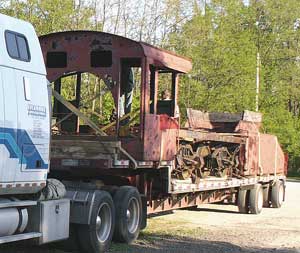 The cab and tender loaded onto a truck.